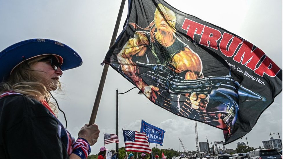 A Florida Trump fan holds a flag depicting him as Rambo, the action star