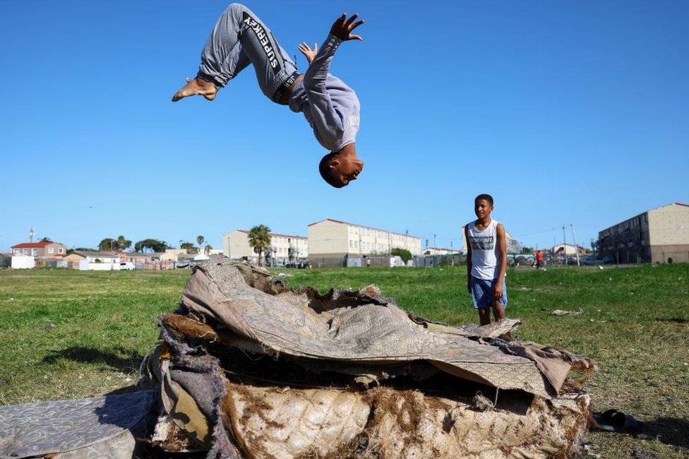 صبي يلعب على مراتب قديمة في هانوفر بارك، وهي منطقة تضررت من عنف العصابات المستمر في كيب تاون، جنوب إفريقيا، 28 سبتمبر/أيلول 2022