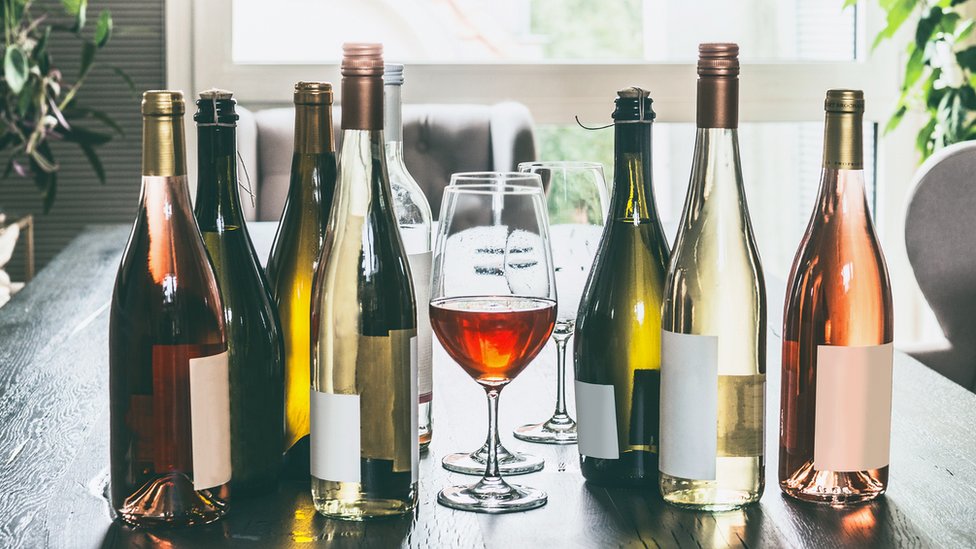Taça de vinho rodeada por garrafas de vinho