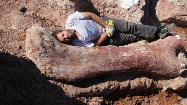 Dr Diego Po lying next to dinosaur bone