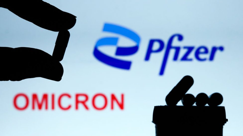Foto ilustrativa de pastillas con el logotipo de Pfizer detrás y la palabra "ómicron".