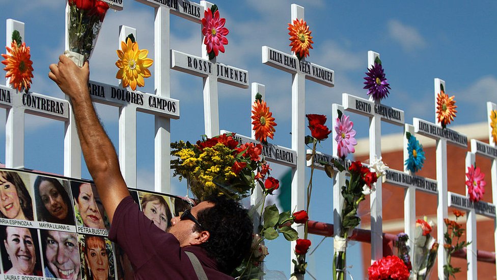 Un pariente de las víctimas del Casino Royale coloca flores en una cruz durante la conmemoración del primer aniversario del crimen en Monterrey, México, el 25 de agosto de 2012. 52 personas murieron el 25 de agosto de 2011, cuando miembros del cartel de drogas Los Zetas roció el Casino Royale con gasolina y lo incendió.
