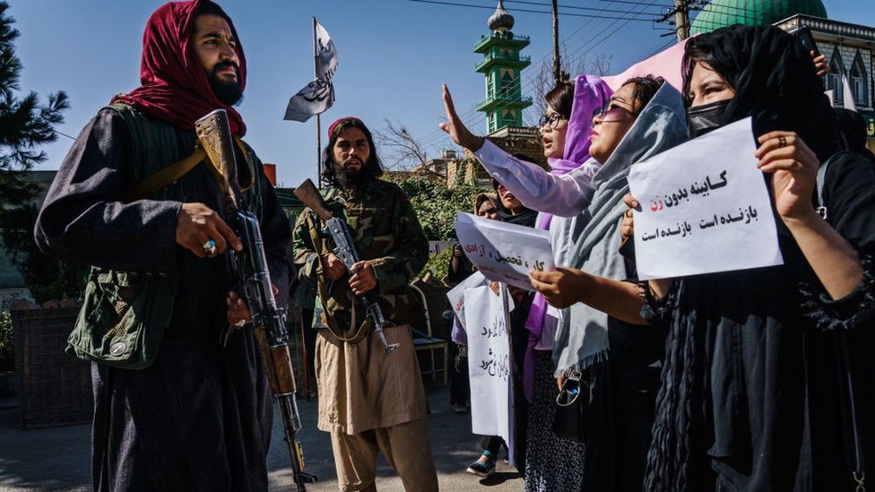 A Taliban fighter stares at demonstrators in Kabul