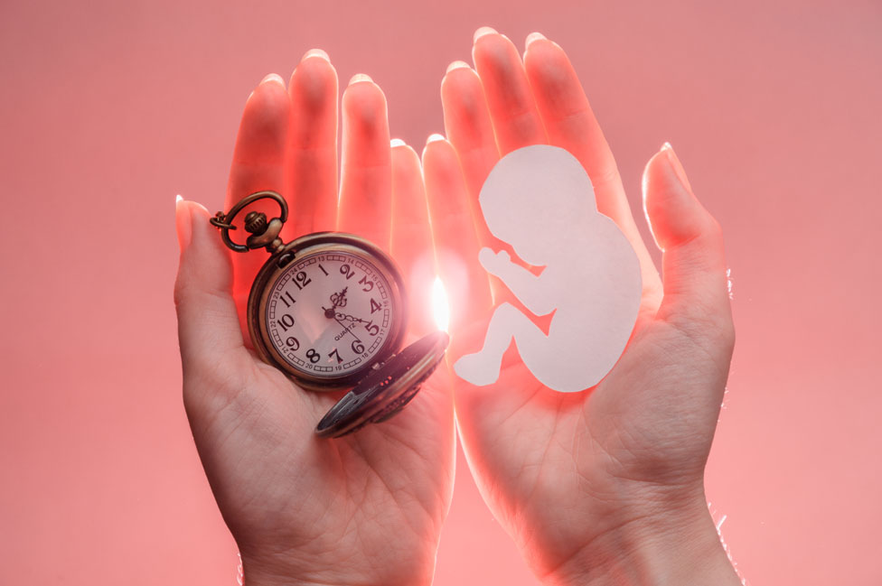 Art showing a woman holding a pocket watch and a baby silhouette