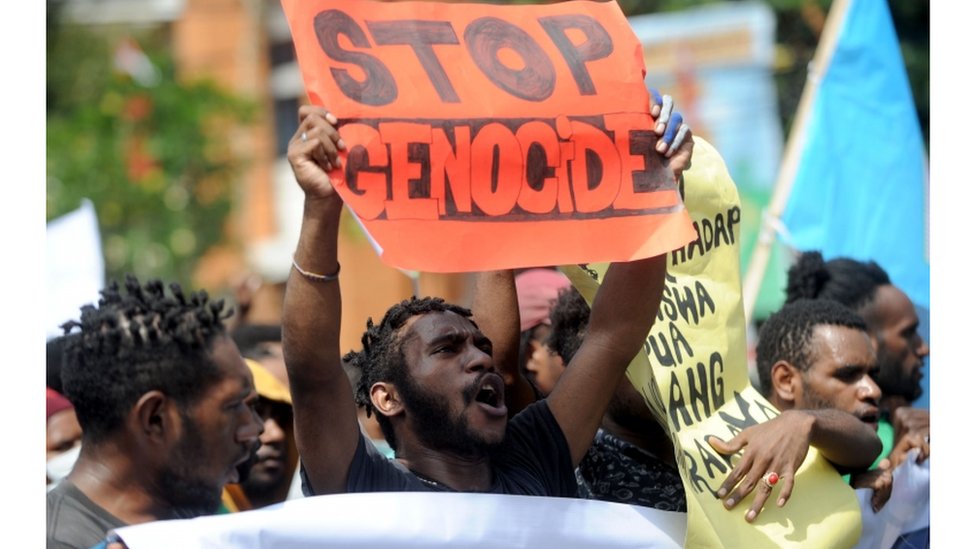 Протестующие держат плакат с надписью «Остановите геноцид»