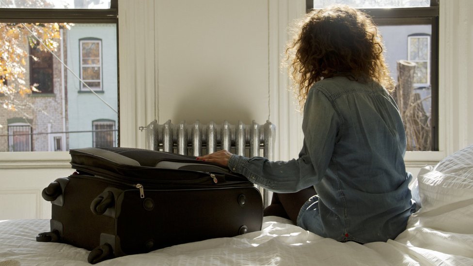 Mujer sobre una cama de un alojamiento Airbnb.