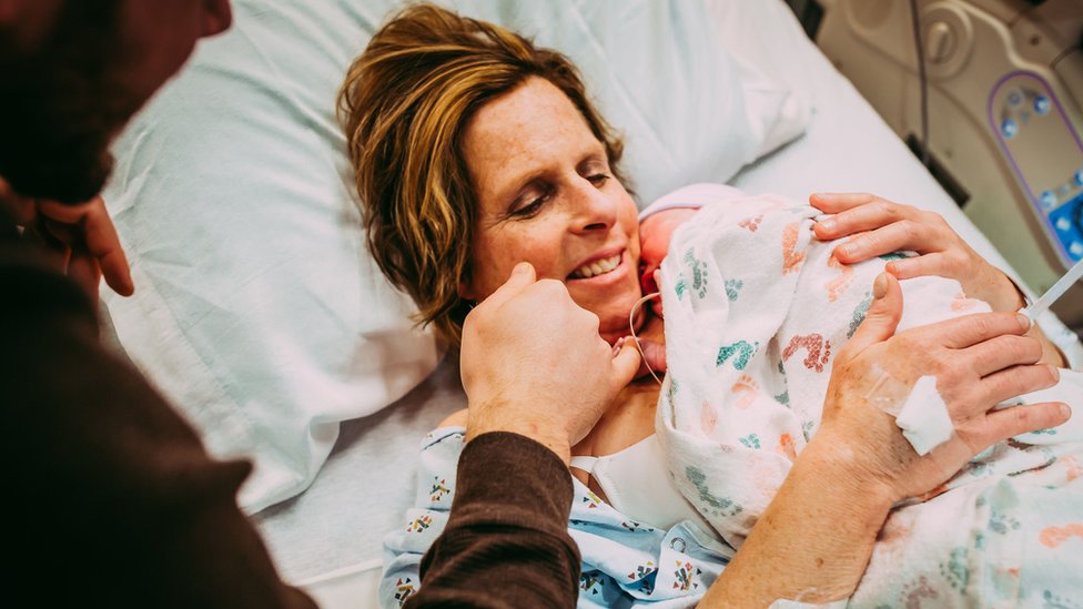 Женщина, Сесил Эледж, держит на руках свою новорожденную внучку Уму.