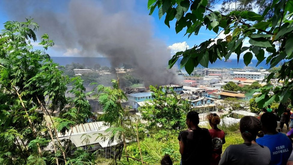 Smoke rises from a burnt out buildings in Honiara's Chinatown on November 26, 2021 after two days of rioting which saw thousands ignore a government lockdown order, torching several buildings around the Chinatown district including commercial properties and a bank branch.