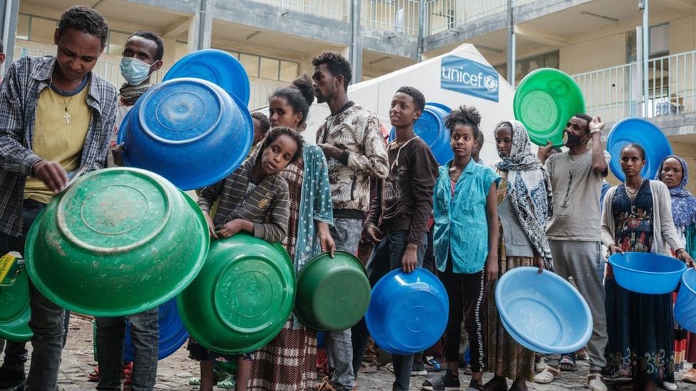 Pessoas que fugiram da violência na região de Tigré, na Etiópia, esperam para receber injeras, o alimento básico da Etiópia feito de pão achatado fermentado azedo, como única refeição do dia na escola secundária May Weyni, que agora abriga 10.500 deslocados como um campo de deslocados, em Mekele, a capital da região de Tigray, em 19 de junho de 2021