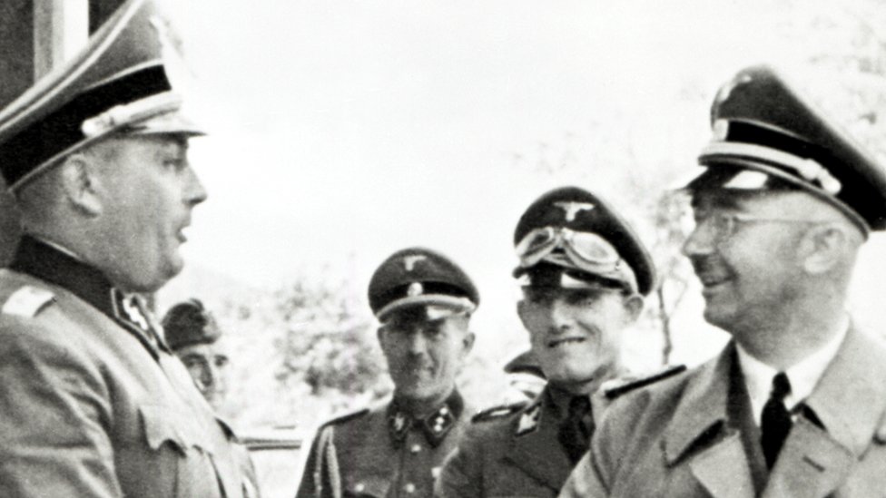 Генрих Гиммлер (справа), пятизвездочный генерал, во время посещения лагеря Освенцим в Польше, где он осматривает фабрики Моновица. 18 июля 1942 г.