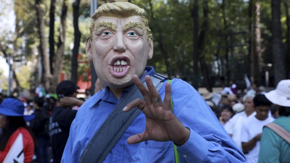 Мужчина в маске с изображением президента США Дональда Трампа во время марша с требованием уважения к Мексике и ее мигрантам, 12 февраля 2017 г.