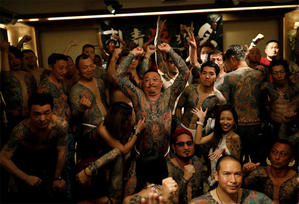 A group of people with body tattoos pose for a photo
