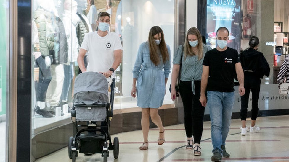 Personas con máscaras caminan por el centro comercial en España