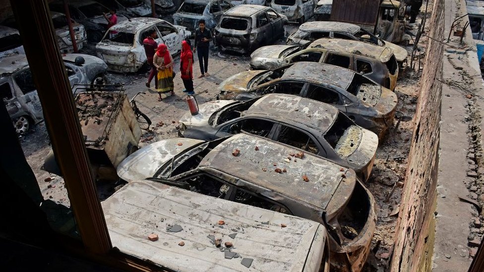 Жители пытаются идентифицировать свои обгоревшие автомобили на стоянке для автомобилей, которая была подожжена в результате недавних столкновений в районе Мустафа Абад в Нью-Дели 29 февраля 2020 года.