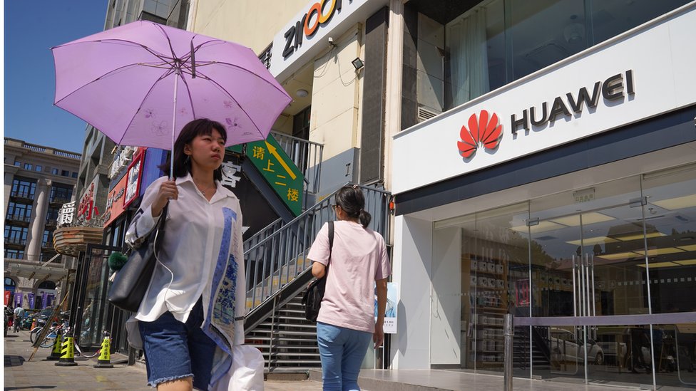 Люди проходят мимо магазина Huawei 1 июля 2019 года в Дундацяо, район Чаоян, Пекин.