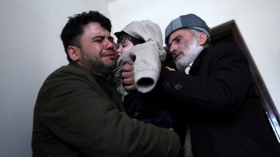 Hamid Safi, a 29-year-old taxi driver who had found baby Sohail Ahmadi in the airport, cries as he hands over Sohail to his grandfather Mohammad Qasem Razawi in Kabul