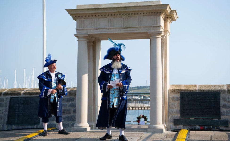 Hombres con trajes históricos en los escalones de Mayflower, el lugar donde se cree que los peregrinos abordaron el Mayflower hace 4 siglos en Plymouth, Inglaterra, en la celebración del aniversario.
