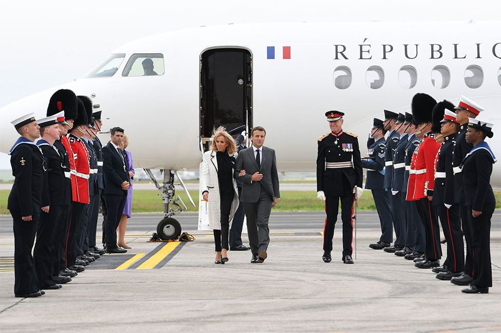 French president Emmanuel Macron and his wife Brigitte Macron step off their plane and are greeted by members of the Navy and Armed Forces