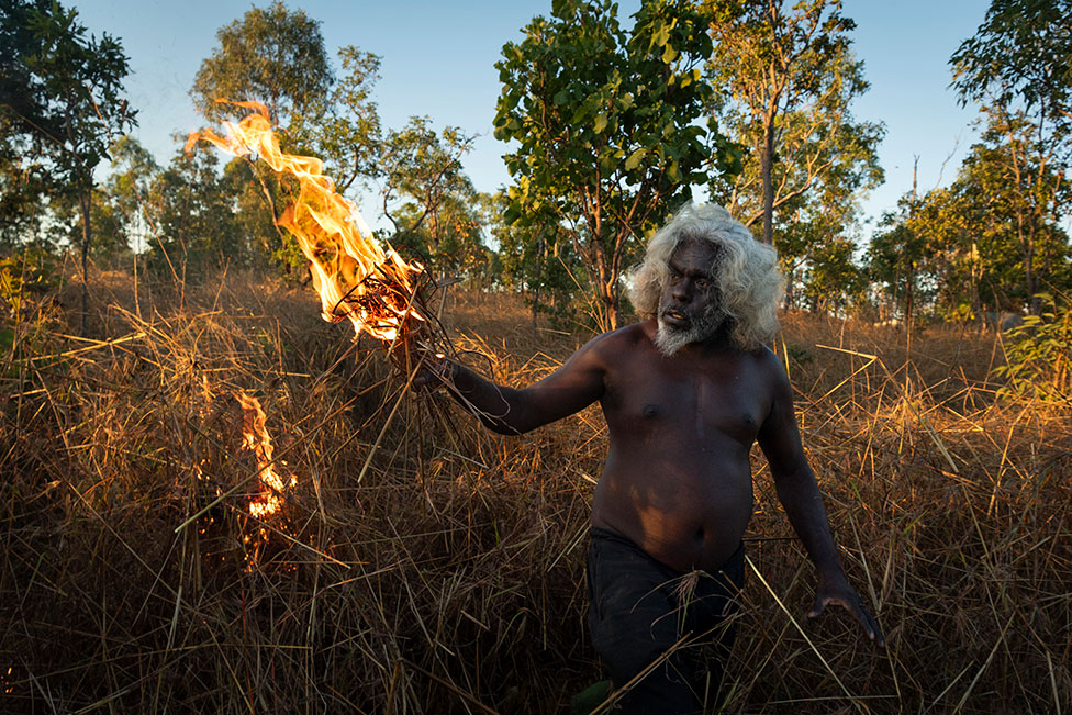 O cacique de Nawarddeken, Conrad Maralngurra, queima grama para proteger a comunidade de Mamadawerre dos 'incêndios florestais' do final da temporada, em Mamadawerre, Arnhem Land, Austrália, em 3 de maio de 2021