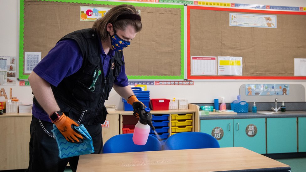 A member of staff disinfects tables at a primary school