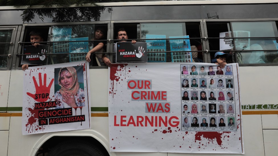Un autobús con pintura roja y pancartas con los rostros de estudiantes muertas
