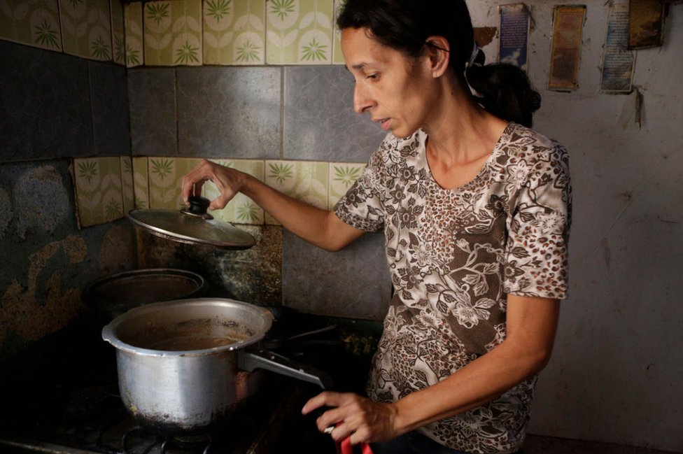 Mujer en una cocina con una cazuela.
