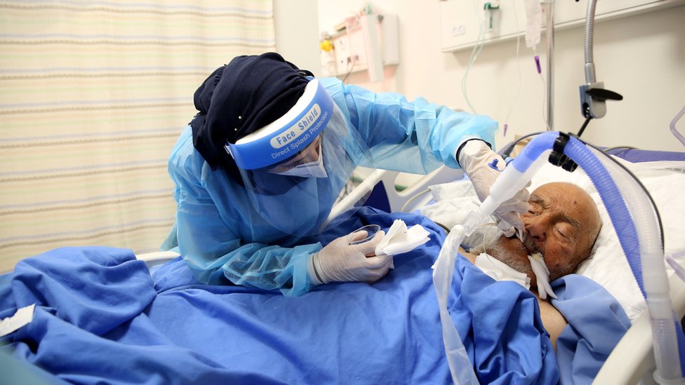 عاملة طبية تفحص مريضا بكوفيد-19 في مستشفى بالضفة الغربية