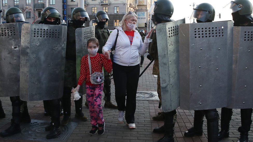 Женщина с ребенком разговаривает с сотрудниками ОМОНа, блокировавшими территорию во время митинга на проспекте Независимости 20 сентября