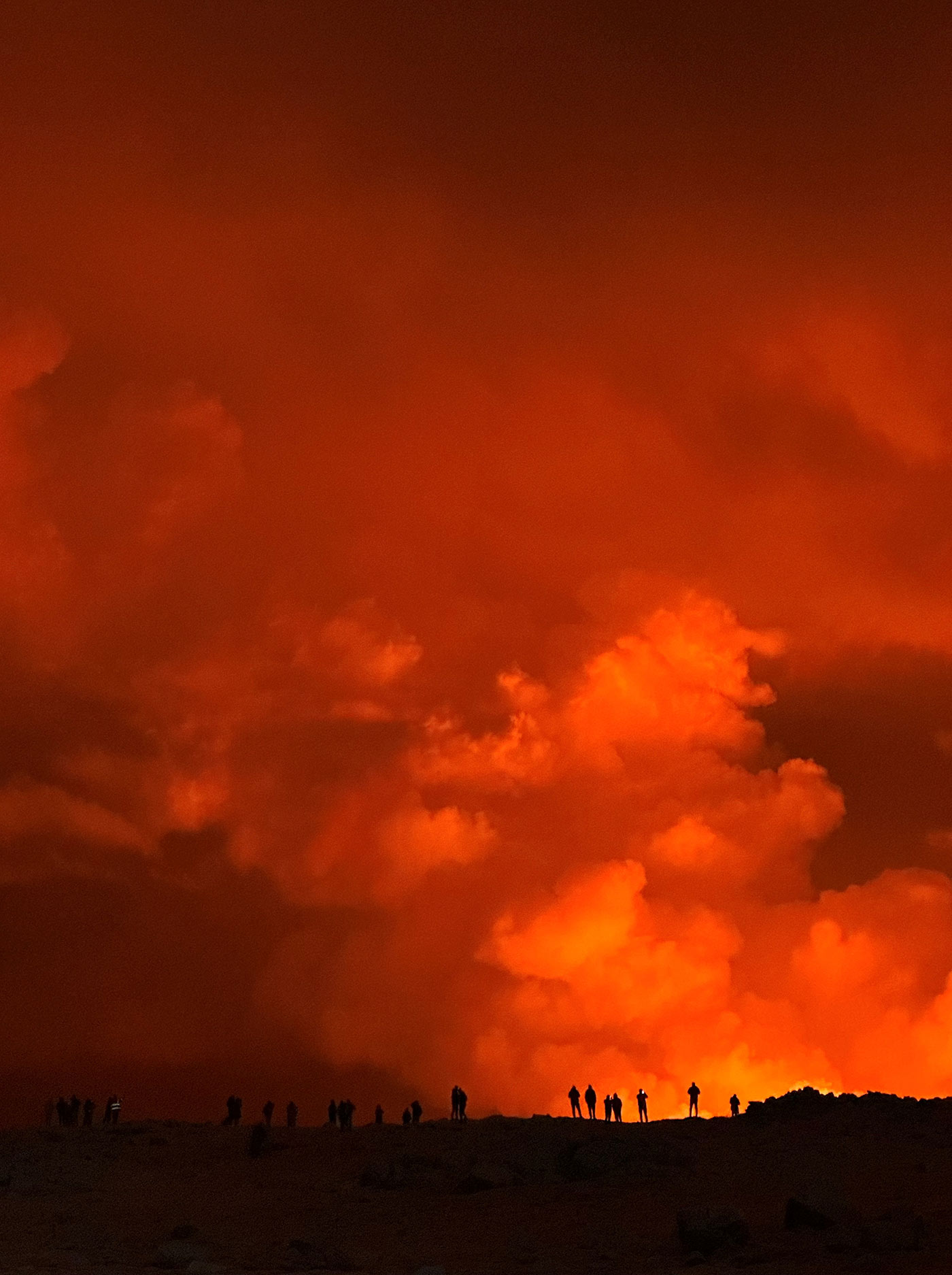 People silhouetted against the glow from the volcano's eruption, in this view from Keflavik, Iceland - 18 December 2023