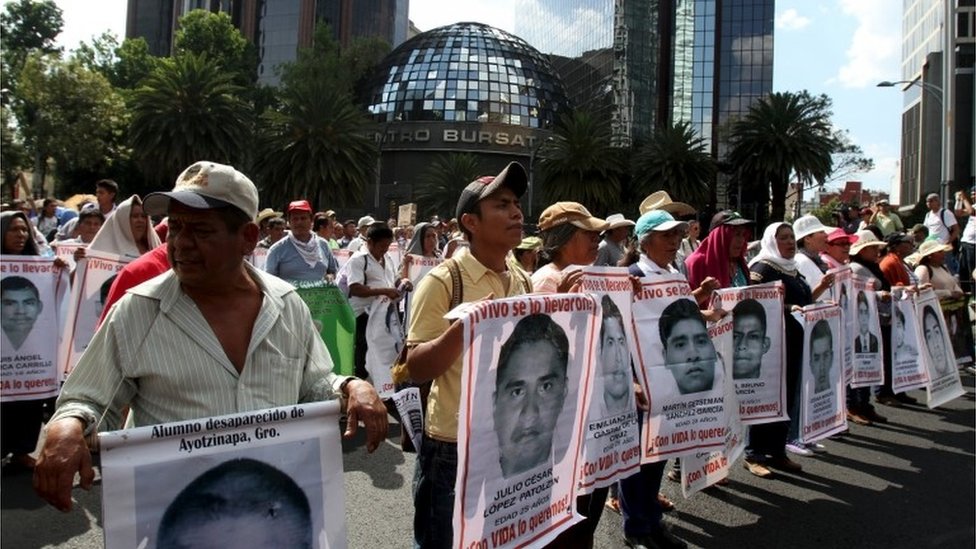 Родственники несут фотографии некоторых из 43 пропавших без вести студентов во время марша по случаю десятимесячной годовщины их исчезновения в Мехико (26.07.2015)