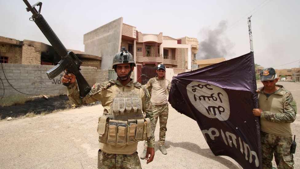 Солдаты иракского правительства держат так называемый флаг Исламского государства после битвы в Фаллудже.