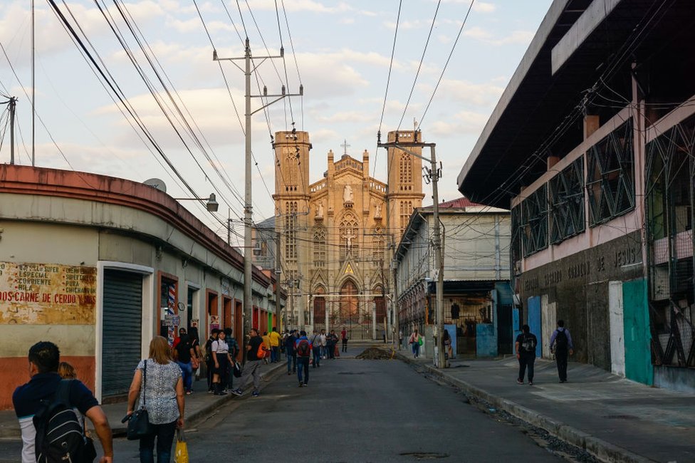 La gente camina en una calle frente a la Iglesia El Calvario el 29 de marzo de 2023 en San Salvador, El Salvador.