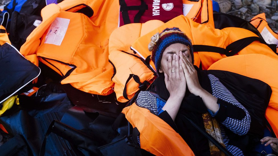 Женщина реагирует вскоре после прибытия с другими мигрантами и беженцами на греческий остров Лесбос после пересечения Эгейского моря из Турции, 14 октября 2015 года.