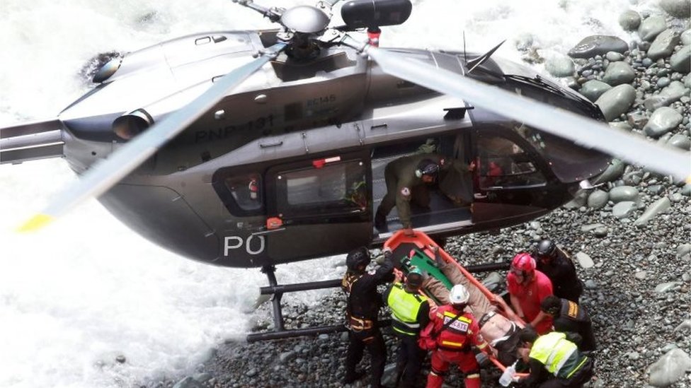 Группа аварийно-спасательных служб загружает пострадавшего в вертолет, который приземлился на каменистом берегу, во время спасательных операций после того, как автобус упал на север Панамериканского шоссе, примерно в 45 километрах от Лимы, Перу, 2 января 2018 г. автор: Agencia Andina)
