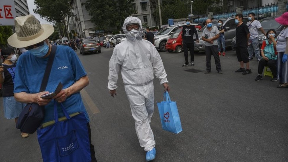 Seorang pekerja kesehatan di Beijing memegang tas berwarna biru alat kesehatan.