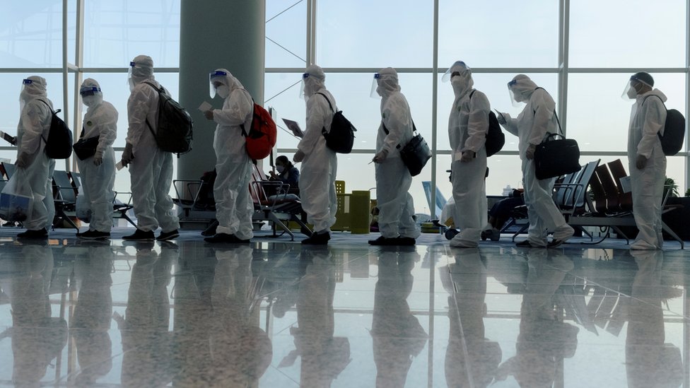 香港國際機場內一群身穿醫用個人防護衣（PPE）的旅客排隊凖備登機（9/7/2021）