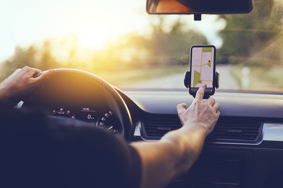 Un hombre utilizando el GPS de su celular mientras conduce