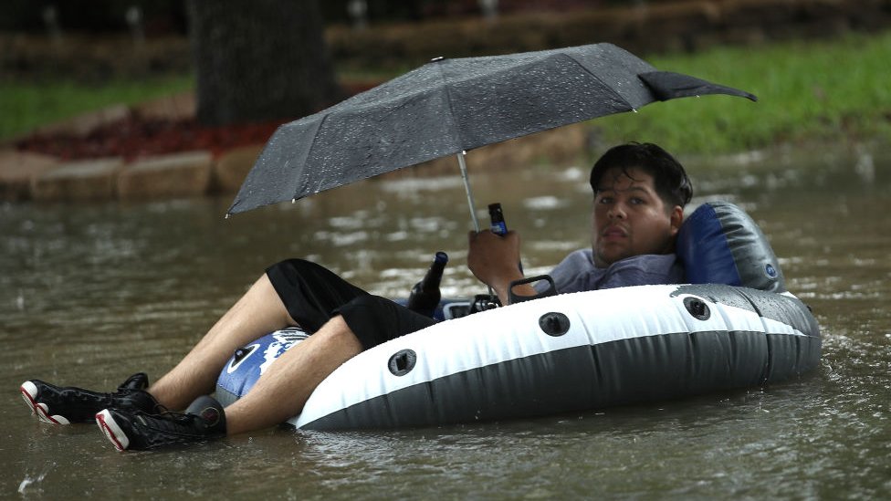Alrededor de 2.000 personas han sido rescatadas de zonas donde el agua alcanzaba el techo de las viviendas. Un hombre bajo un paraguas y a bordo de una lancha huye en una calle inundada de Houston.