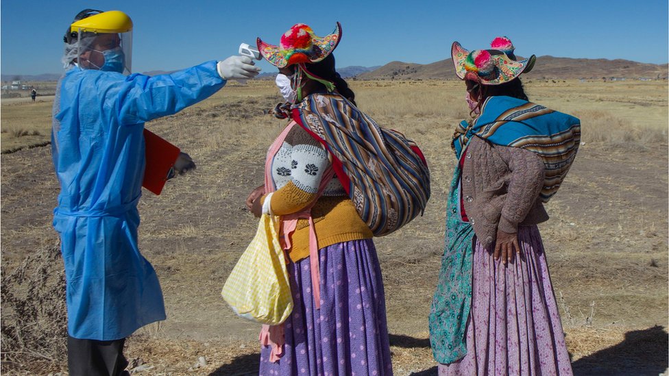 Un médico toma la temperatura a dos mujeres en un área rural de Perú.