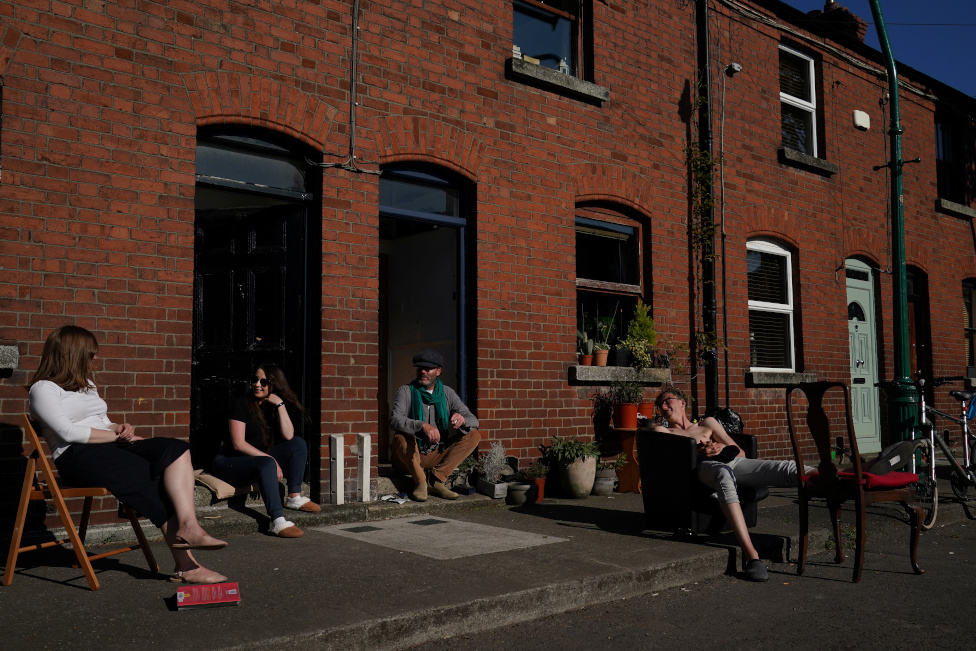 People chat while social distancing outside their homes