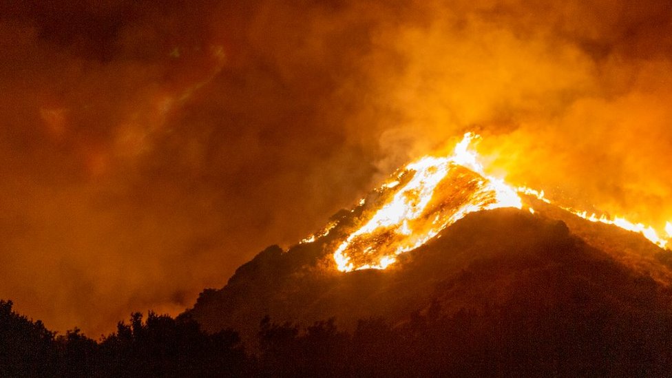 A wildfire engulfs a hillside in California, filling the air with smoke