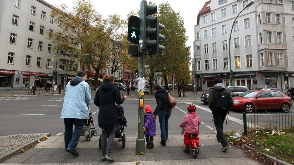 Группа родителей и детей переходят улицу в бывшем восточногерманском районе Пренцлауэр-Берг