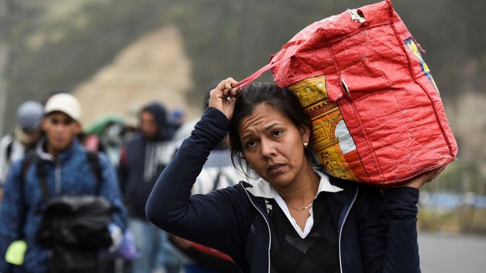Una migrante venezolana con su maleta sobre los hombros.