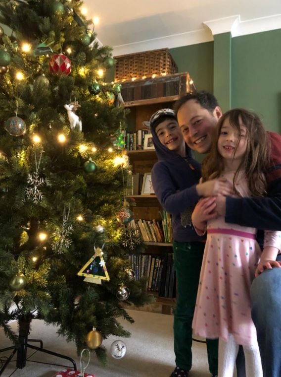 Chris Slegg junto a sus hijos al lado del árbol de Navidad.