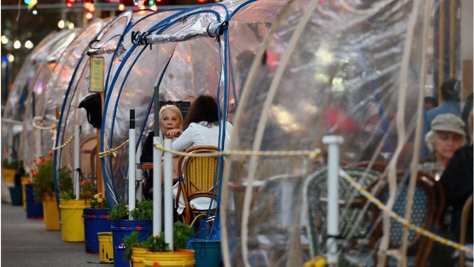 Посетители Нью-Йорка едят на улице в пластиковых пузырях