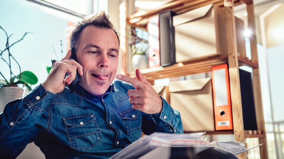 Un hombre habla por teléfono mientras se señala la lengua.