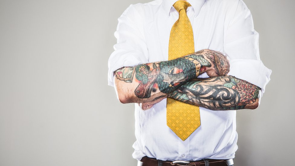 Hombre con tatuajes, camisa y corbata