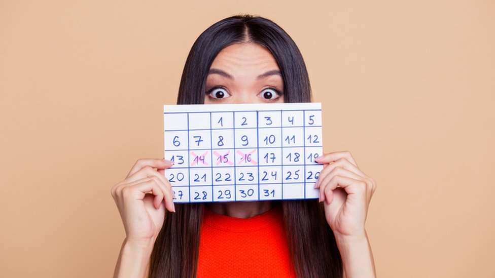 Mujer sostiene un calendario con sus días de menstruación.