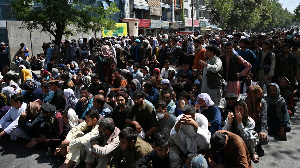 People sitting outside a bank waiting to withdraw money in Kabul in September 2021