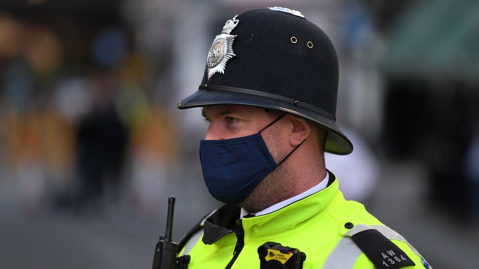 Офицер полиции в защитном лице прикрывает патрули в Сохо в Лондоне